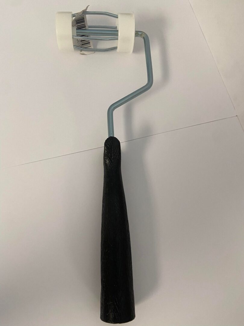 A long paint roller with a black handle