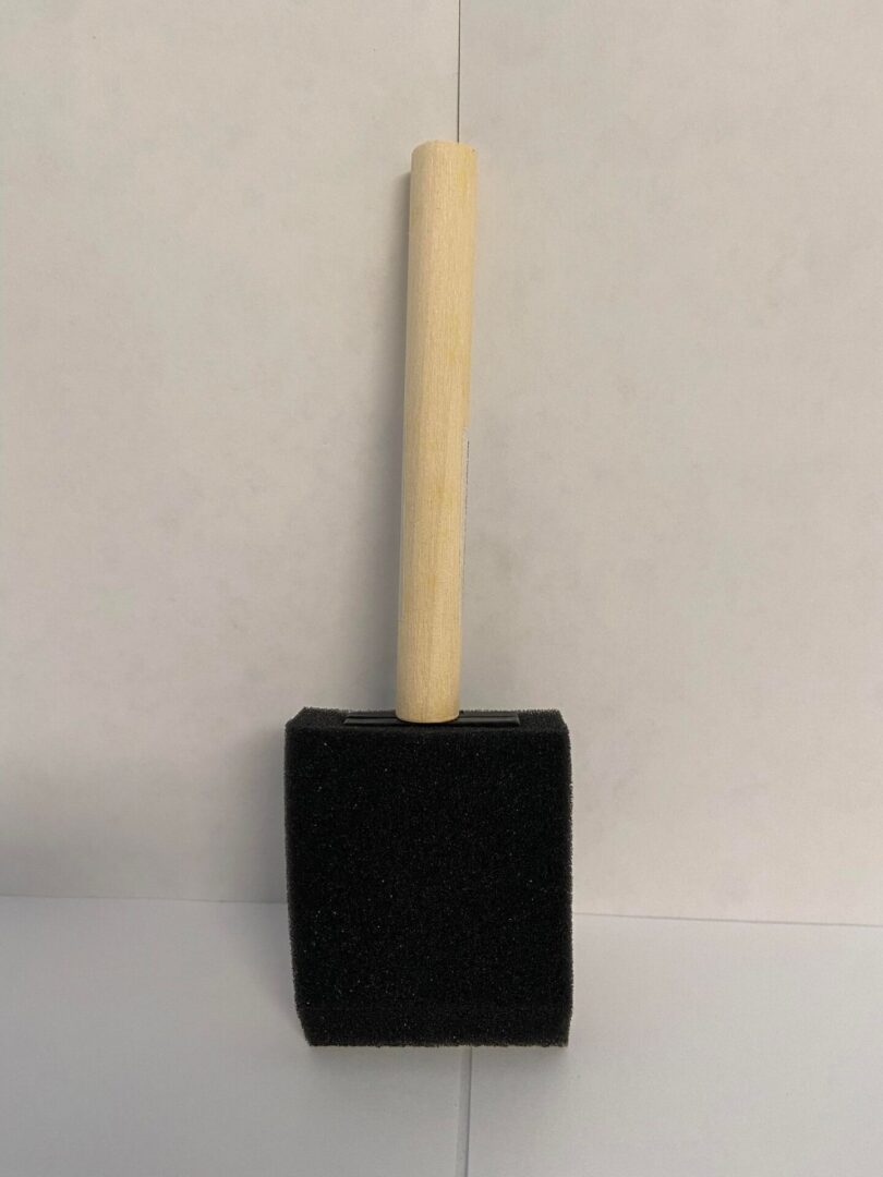 A black foam brush with a wooden handle